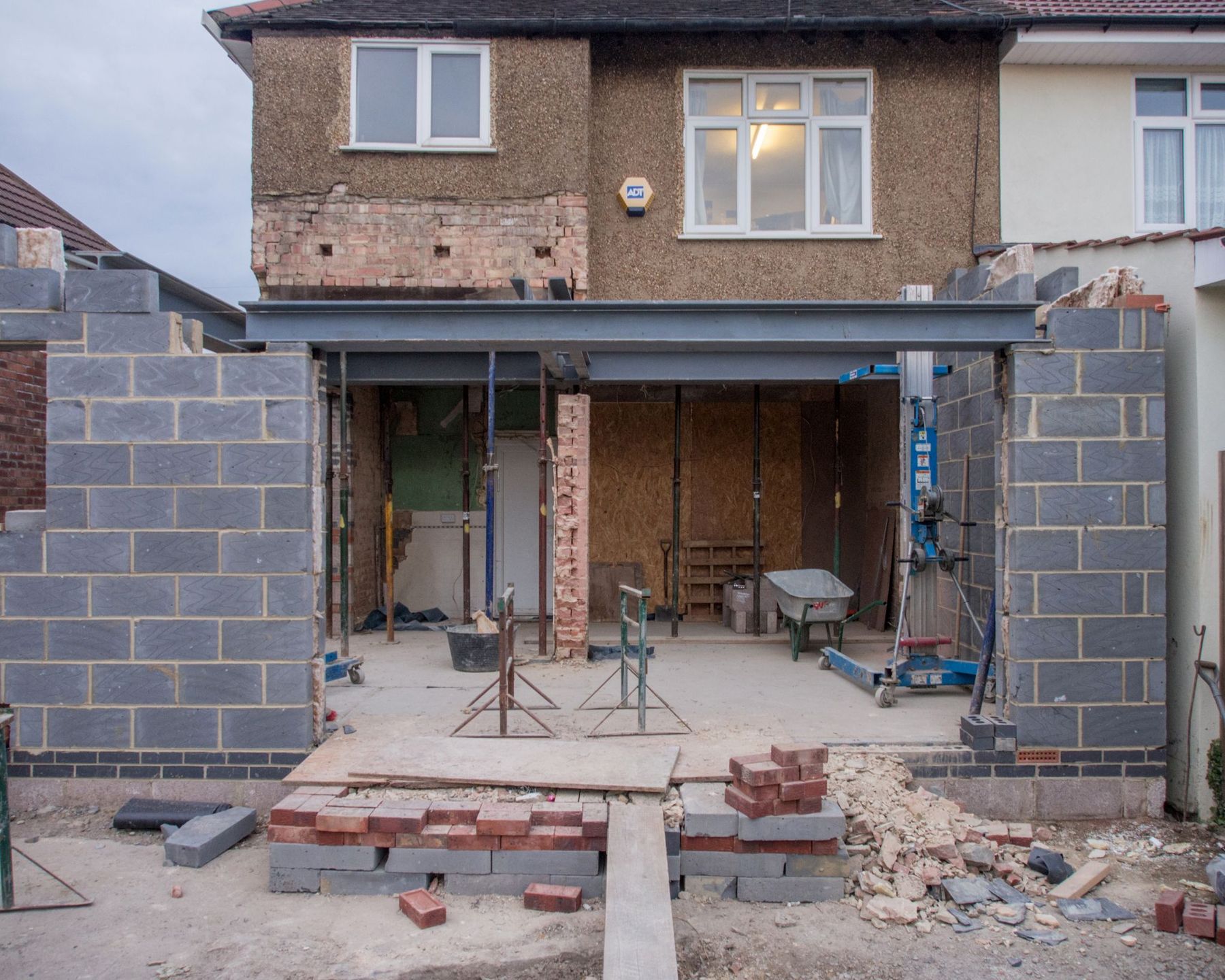 The rear of a house opened up for an extension — blockwork up, steel beam in, ready for the roof