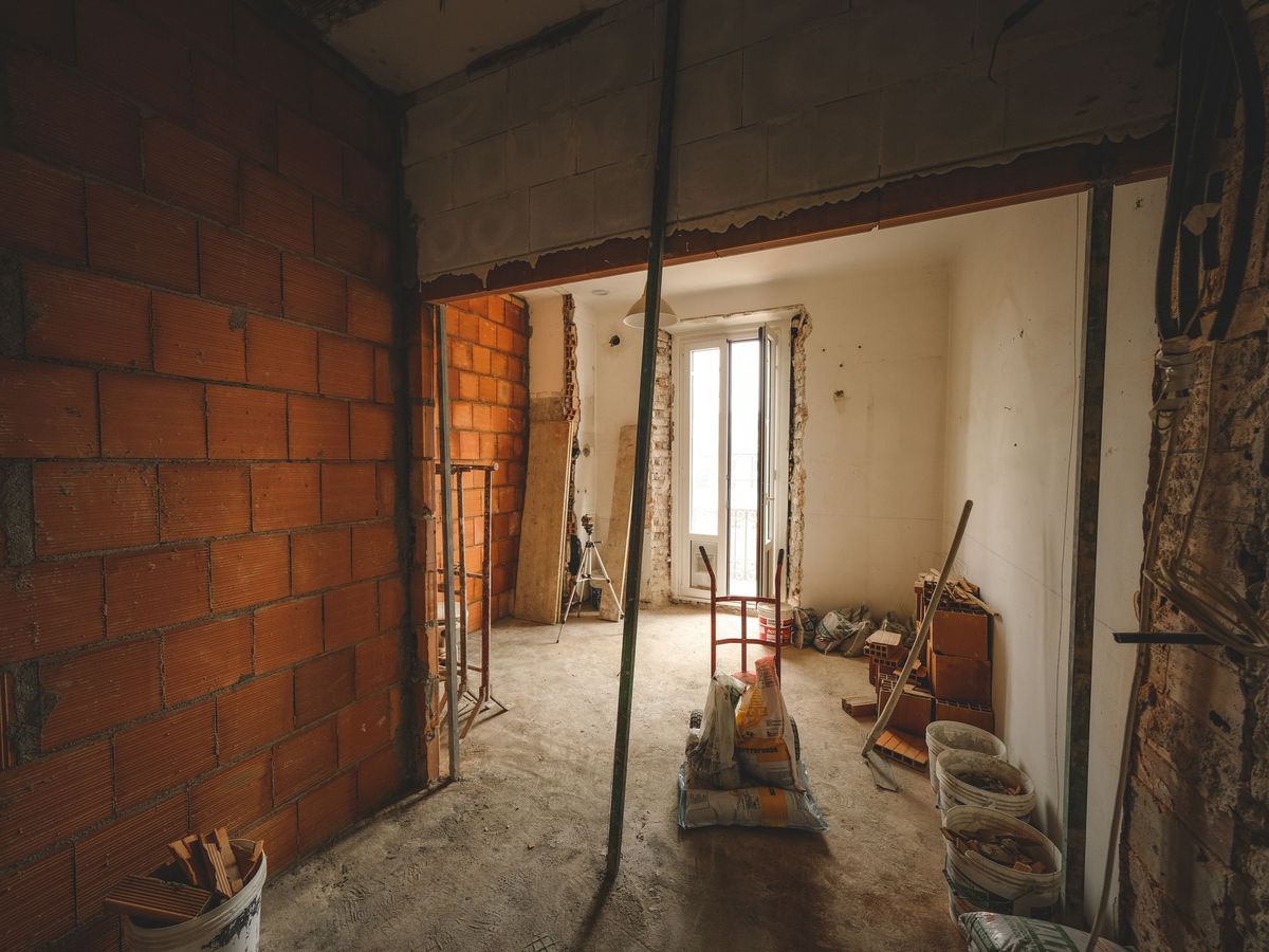 A room stripped back to brick with adjustable props holding the structure while an opening is formed